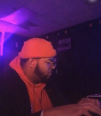 a man in an orange hat is playing a keyboard