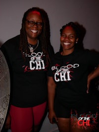 two women standing in front of a fan