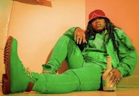 a woman sitting on the floor in green pants and a hat